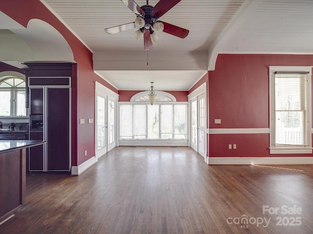 unfurnished living room featuring a healthy amount of sunlight, dark wood finished floors, and a ceiling fan