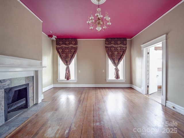 unfurnished living room featuring an inviting chandelier, a fireplace, ornamental molding, and hardwood / wood-style floors