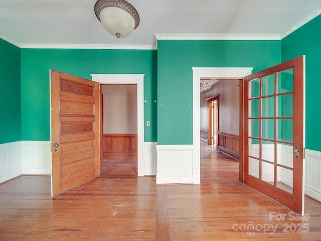 spare room featuring ornamental molding, wood finished floors, and wainscoting