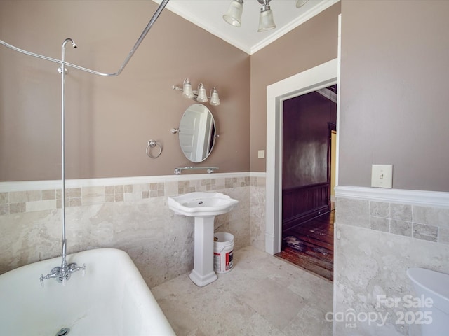 full bathroom with wainscoting, a soaking tub, tile walls, and crown molding