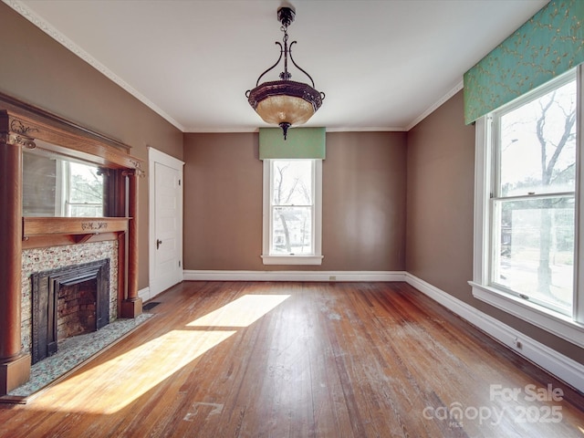 unfurnished living room with a tiled fireplace, a wealth of natural light, and baseboards