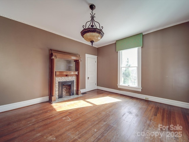 unfurnished living room with hardwood / wood-style flooring, baseboards, crown molding, and a tile fireplace