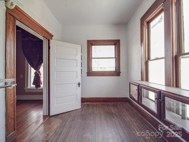 spare room featuring baseboards and dark wood-style flooring