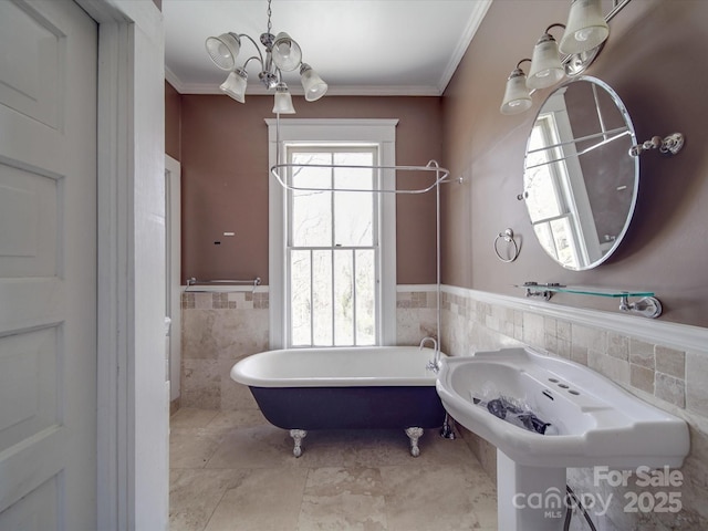 bathroom featuring crown molding, tile walls, a freestanding bath, an inviting chandelier, and wainscoting