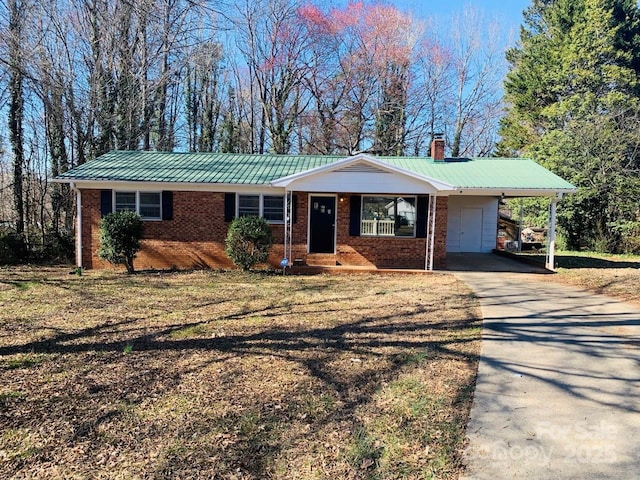 ranch-style house with concrete driveway, a chimney, metal roof, a carport, and brick siding