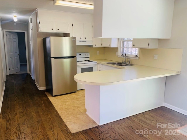 kitchen featuring white electric stove, freestanding refrigerator, a sink, a peninsula, and under cabinet range hood