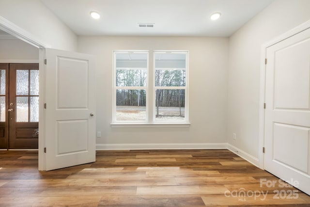 foyer with light wood finished floors, baseboards, visible vents, and french doors