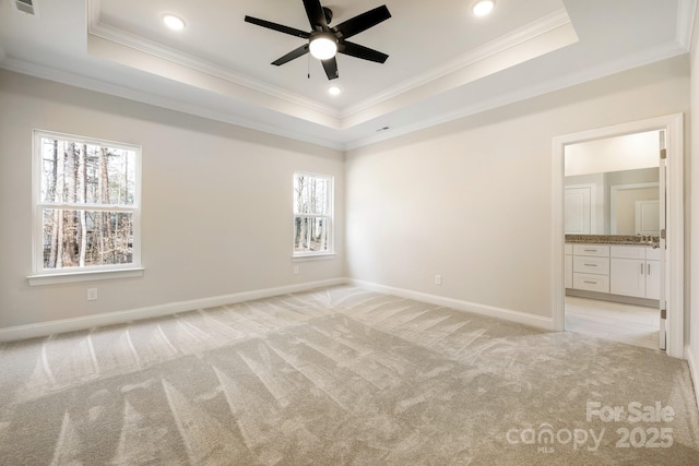 unfurnished bedroom featuring baseboards, ornamental molding, a raised ceiling, and light colored carpet