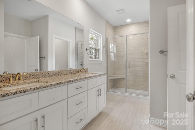 bathroom with double vanity, a stall shower, a sink, and visible vents