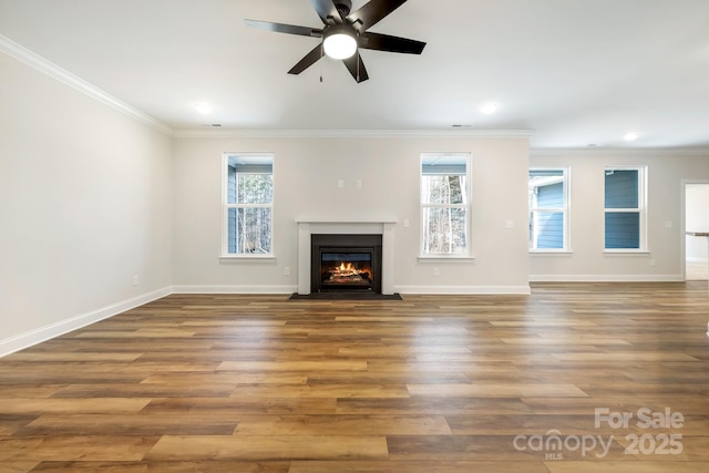 unfurnished living room featuring wood finished floors, plenty of natural light, a fireplace with flush hearth, and crown molding