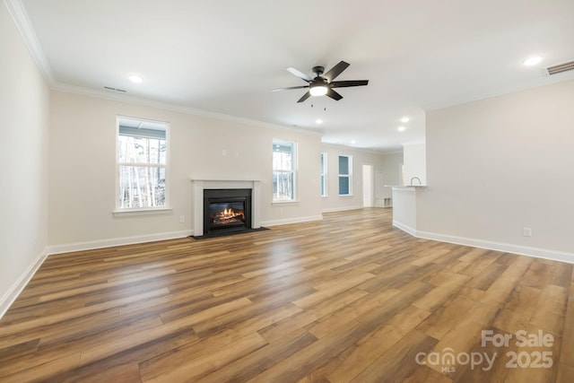 unfurnished living room featuring ornamental molding, baseboards, visible vents, and light wood finished floors