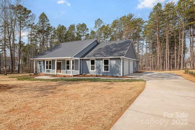 view of front of house featuring driveway, an attached garage, covered porch, a front lawn, and board and batten siding