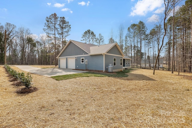 view of side of property featuring board and batten siding, an attached garage, concrete driveway, and a yard