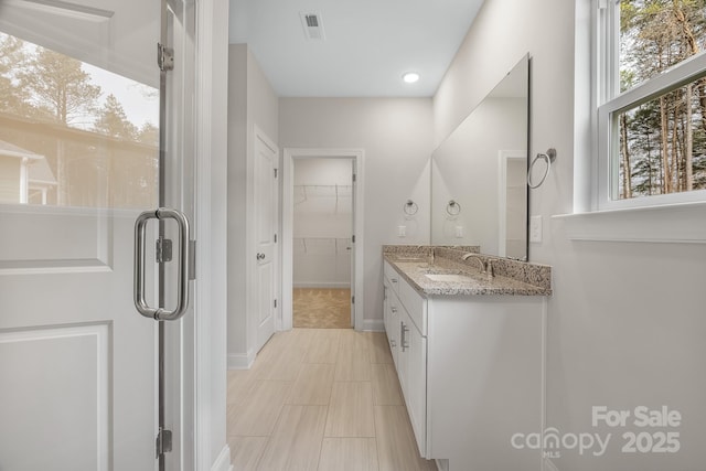 bathroom with a walk in closet, visible vents, and vanity