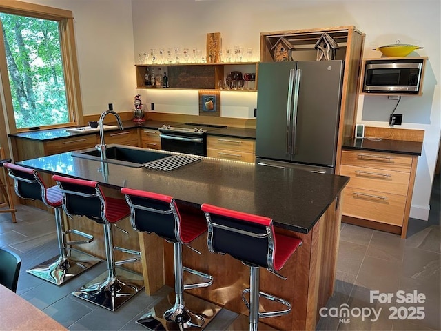 448 Mt Mitchell Dr, Burnsville, NC 28714 - kitchen with a sink, a breakfast bar area, a center island with sink, stainless steel appliances, and dark countertops