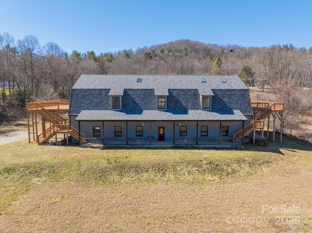 view of front facade featuring a front yard, roof with shingles, stairway, and a gambrel roof