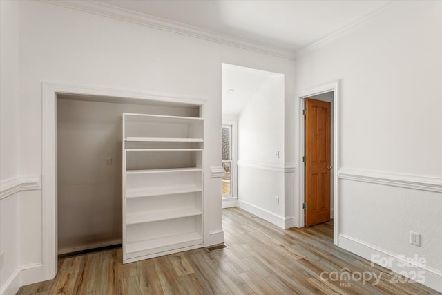 interior space with ornamental molding, wood finished floors, and baseboards