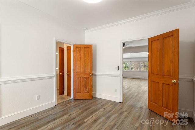 empty room featuring baseboards, wood finished floors, and crown molding