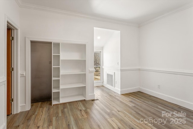 unfurnished bedroom with baseboards, visible vents, wood finished floors, and ornamental molding