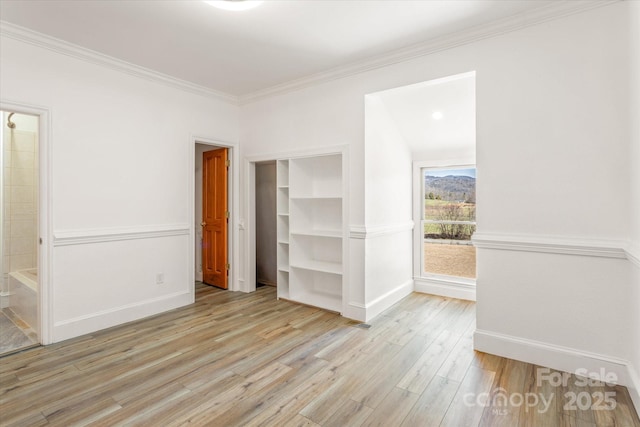 unfurnished bedroom featuring light wood-type flooring, baseboards, and crown molding