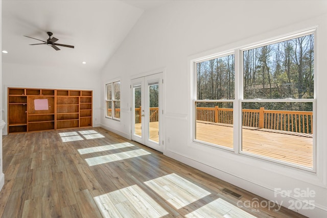 unfurnished living room with ceiling fan, high vaulted ceiling, wood finished floors, visible vents, and french doors