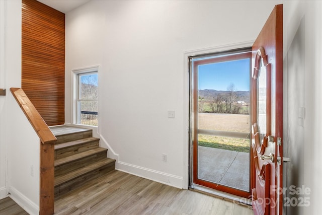 entryway with light wood-style flooring, stairs, and baseboards