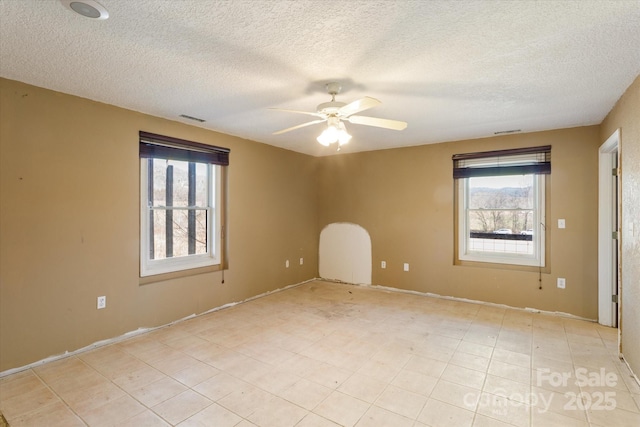 empty room featuring a ceiling fan, visible vents, and a textured ceiling