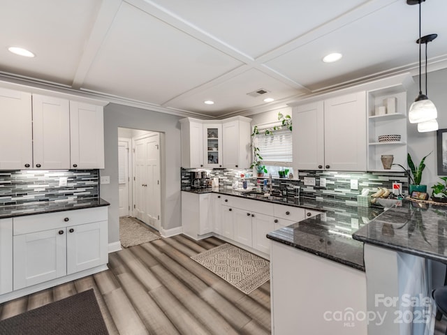 kitchen with open shelves, light wood-style floors, hanging light fixtures, white cabinetry, and a sink