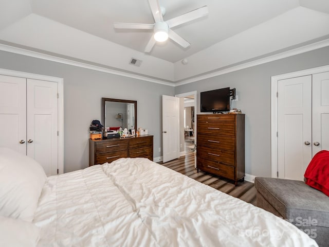 bedroom featuring visible vents, lofted ceiling, wood finished floors, a closet, and a raised ceiling