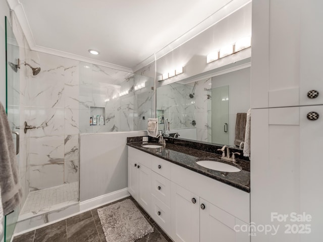 bathroom with a sink, a marble finish shower, double vanity, and crown molding