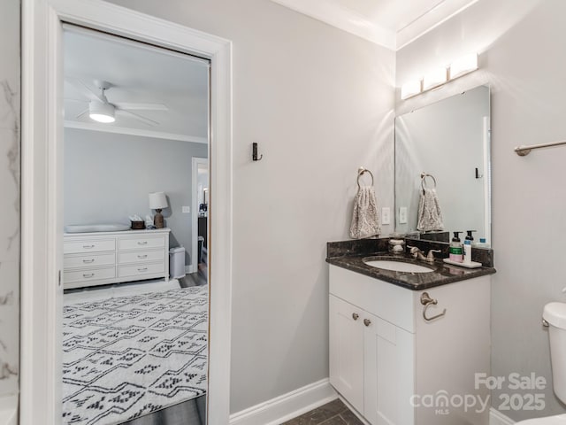 bathroom featuring crown molding, baseboards, toilet, vanity, and a ceiling fan