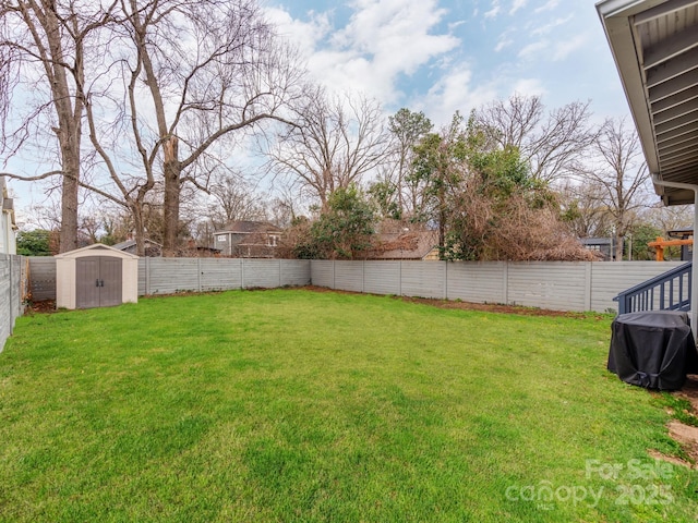 view of yard with an outbuilding, a storage unit, and a fenced backyard