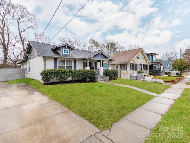 view of front of home featuring brick siding, a front yard, and roof with shingles