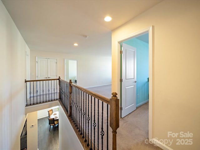 hall with recessed lighting, carpet flooring, baseboards, and an upstairs landing