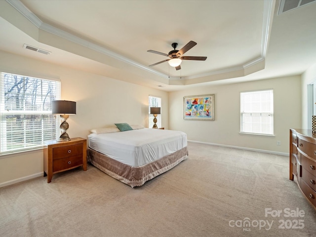 carpeted bedroom featuring ornamental molding, a tray ceiling, visible vents, and baseboards