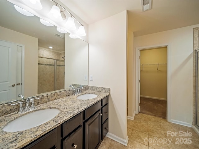 bathroom with a stall shower, a spacious closet, visible vents, and a sink