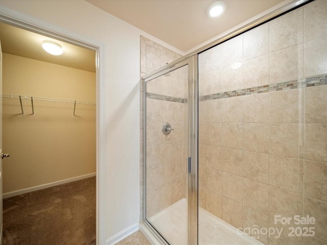 full bathroom with a shower stall, baseboards, and a walk in closet