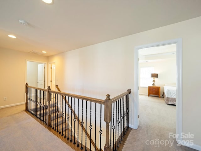 hallway featuring carpet, baseboards, an upstairs landing, and recessed lighting