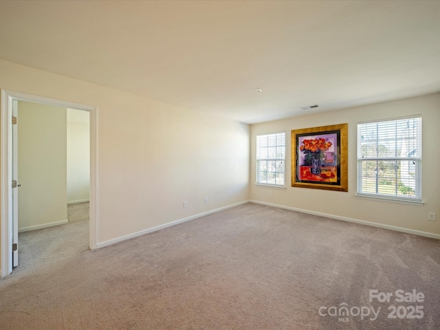 empty room featuring carpet floors, visible vents, and baseboards