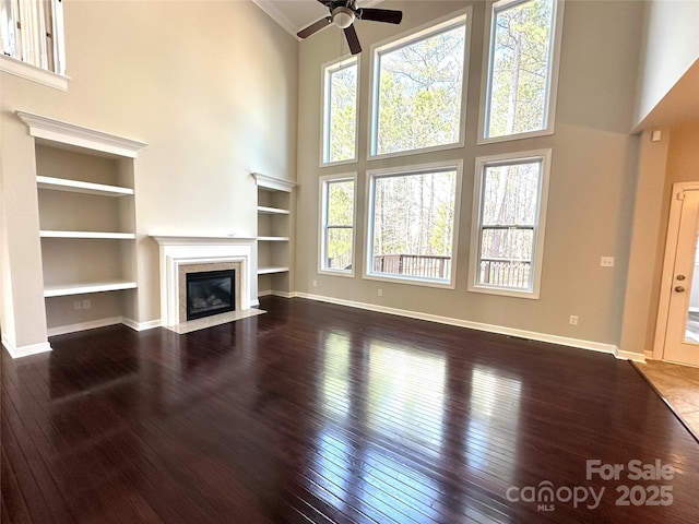 unfurnished living room featuring dark wood-style floors, high vaulted ceiling, a fireplace, and baseboards