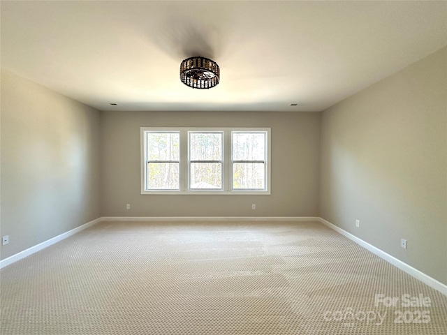 empty room featuring baseboards and light colored carpet