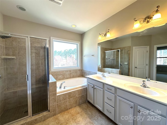 bathroom featuring a stall shower, double vanity, a sink, and a bath