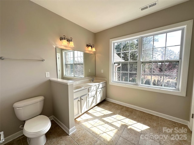 bathroom with double vanity, visible vents, toilet, a sink, and baseboards