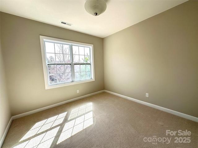 unfurnished room featuring carpet floors, visible vents, and baseboards