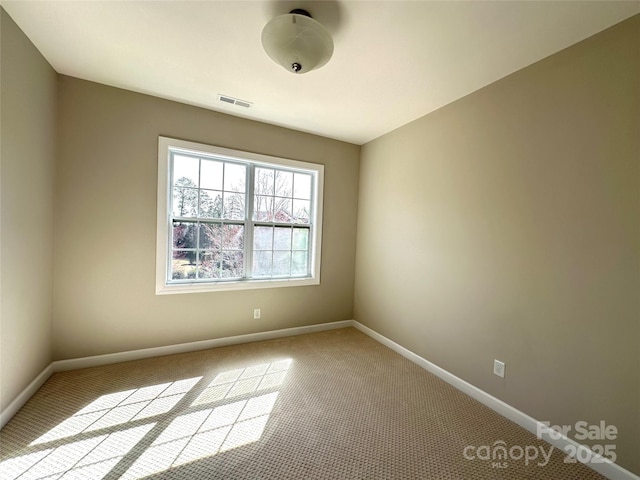 unfurnished room featuring carpet floors, visible vents, and baseboards