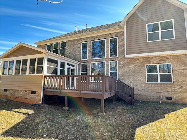 back of house with brick siding, crawl space, a wooden deck, and a sunroom