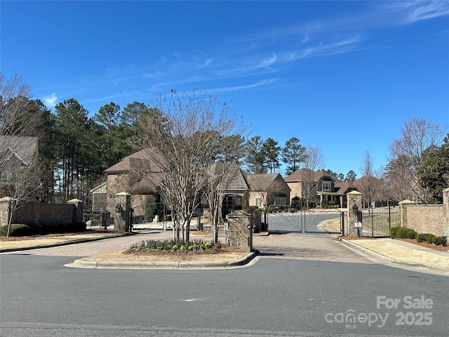 view of street with sidewalks, a gate, a gated entry, and curbs