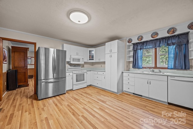 kitchen featuring white appliances, light countertops, a sink, and light wood finished floors