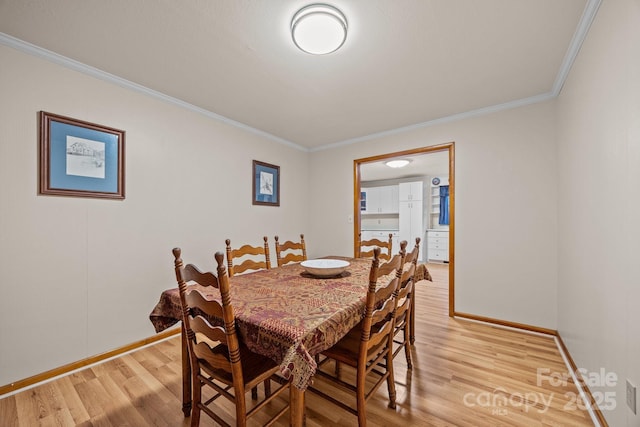 dining space featuring light wood-style floors, baseboards, and crown molding