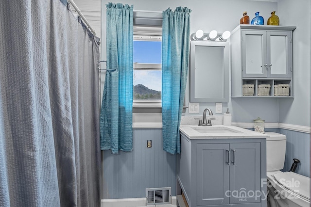 bathroom with toilet, a wainscoted wall, vanity, visible vents, and a shower with curtain